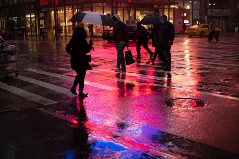 Shoppers walk in a rainstorm Monday in New York. With people staying home as virus cases surge, Cyber Monday was the biggest online shopping day yet, bringing in $10.8 billion in one day. But the entire weekend was disappointing and retailers are bracing for a long winter.