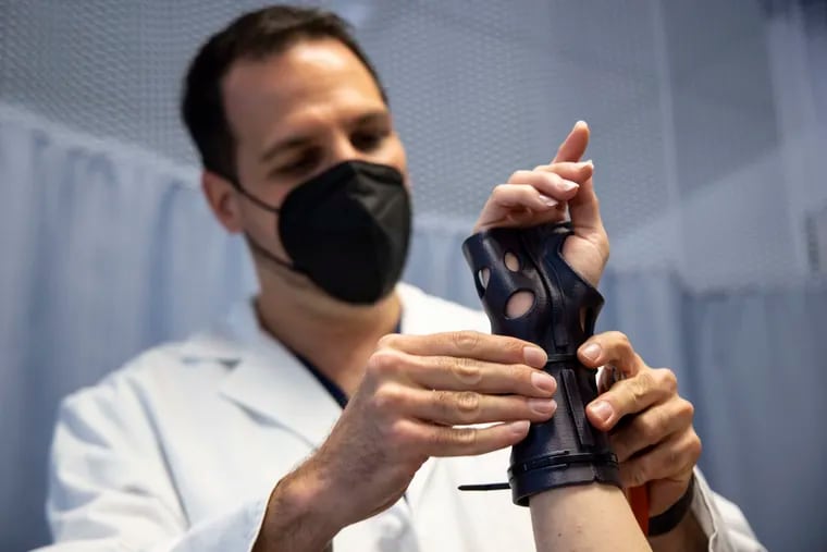 Michael Rivlin, hand and wrist surgeon, shows 3D printed cast on Amy Faulls, at Rothman Orthopaedics in Marlton, N.J.