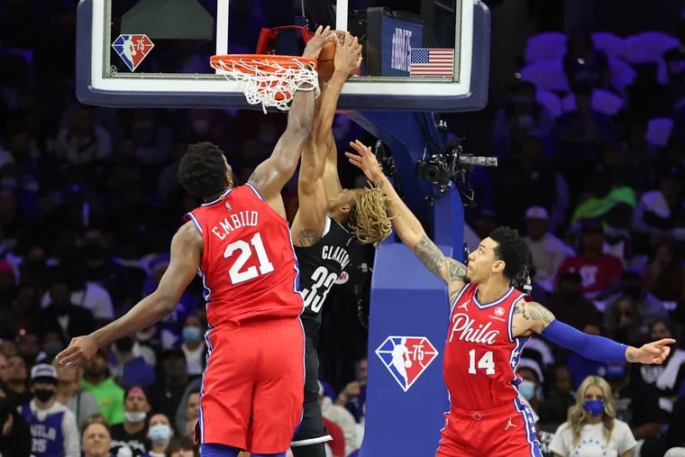 Sixers center Joel Embiid, left, blocks a shot by Nic Claxton of the Nets during his team's 114-109 loss in their home opener at the Wells Fargo Center on Friday.