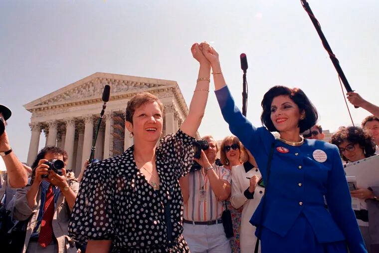 FILE - In this Wednesday, April 26, 1989 file photo, Norma McCorvey, Jane Roe in the 1973 court case, left, and her attorney Gloria Allred hold hands as they leave the Supreme Court building in Washington after sitting in while the court listened to arguments in a Missouri abortion case. A wave of state abortion bans in 2019 has set off speculation: What would happen if Roe v. Wade, the ruling establishing abortion rights nationwide, were overturned? (AP Photo/J. Scott Applewhite, File)