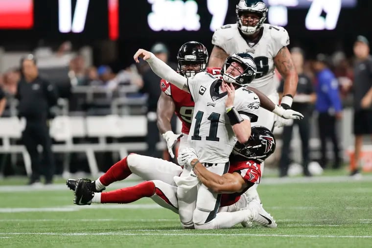 Eagles quarterback Carson Wentz throws the football as he is hit by Falcons linebacker Vic Beasley.