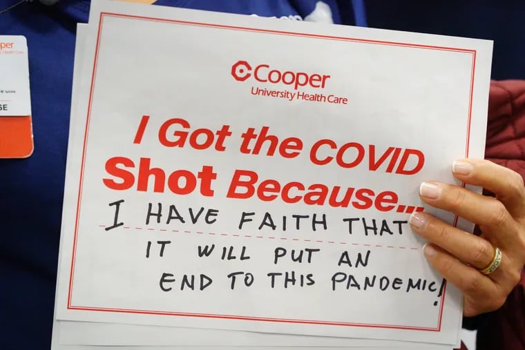 A nurse holds a sign while waiting to receive the COVID-19 vaccine at Cooper University Health Care in December.