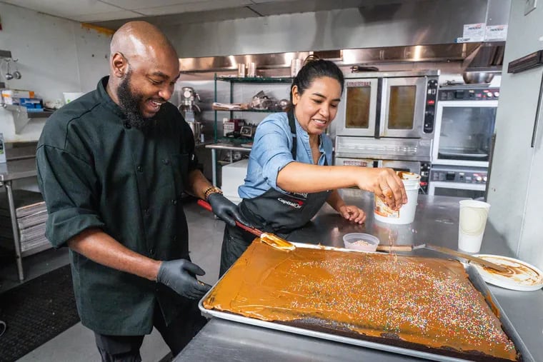 Chef Kijuan Bolger, culinary director of Broad Street Ministry, tops a sheet cake with chef Jezabel Careaga of Jezabel's Cafe in Broad Street Ministry's kitchen.