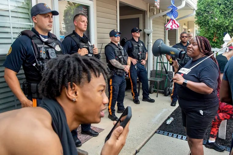 Shanta Smith, right, speaks into a bullhorn on July 5 outside the Mount Laurel, N.J., home of Edward Mathews, after a video went viral of Mathews pushing a Black neighbor with his chest and using racist slurs to address the neighbor and others. Mathews was arrested Monday after protesters gathered at his home for hours. (Tom Gralish/The Philadelphia Inquirer via AP)