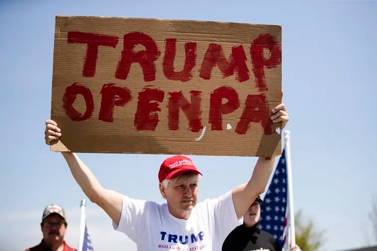 A person holds a sign ahead of President Donald Trump's scheduled visit to an Owens and Minor warehouse in Allentown, Pa., Thursday, May 14, 2020.