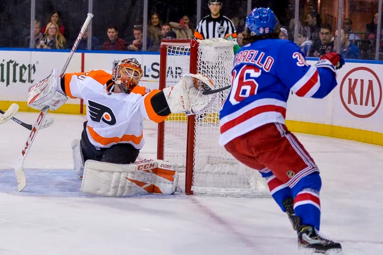 Michal Neuvirth gets his glove on puck and stick of Rangers right wing Mats Zuccarello during the second period of the Flyers' win on Sunday.