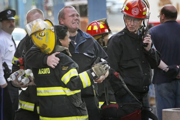 Philadelphia firefighters mourn the loss of their two comrades at the scene of the warehouse fire in Kensington. (Alejandro A. Alvarez / Staff Photographer)