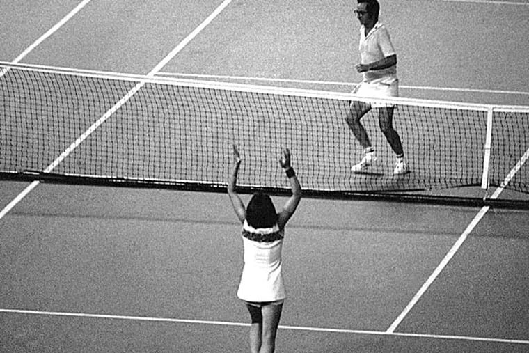 Billie Jean King raises her hands in triumph as Bobby Riggs prepares to hurdle the net. (AP file photo)