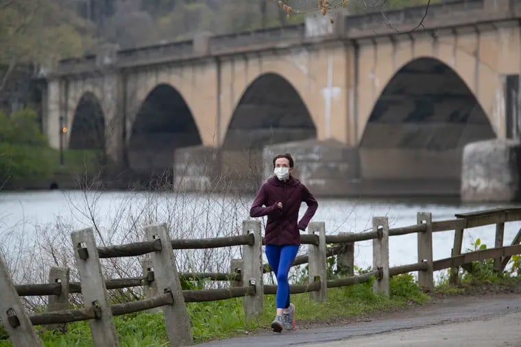 A runner using a mask for protection makes her way along Kelly Drive and past the Columbia Bridge on April 17, 2020.