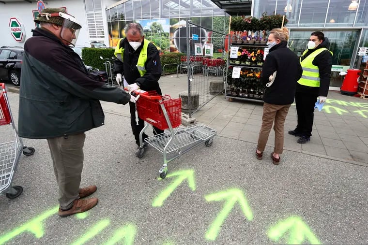 Security employee disinfect shopping carts Monday at the entrance of a garden store in Munich, Germany.  Europe’s biggest economy starts reopening some of its stores and factories after weeks of lockdown because of the coronavirus outbreak.