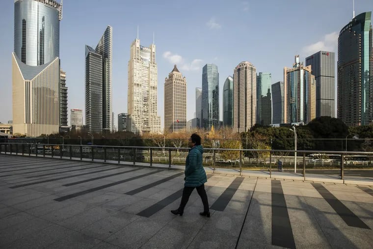 A pedestrian walks on an elevated walkway past buildings in Pudong's Lujiazui Financial District in Shanghai.
