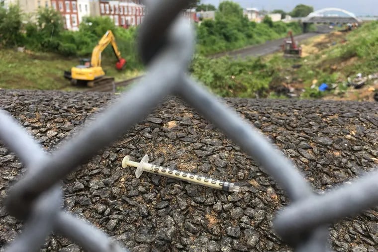 A used syringe rests on the bridge above the Conrail railroad tracks at B Street in Philadelphia on Aug. 3, 2017.