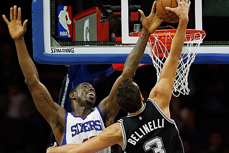 The Spurs' Marco Belinelli dunks over the Sixers' Henry Sims during the second quarter. (Yong Kim/Staff Photographer)