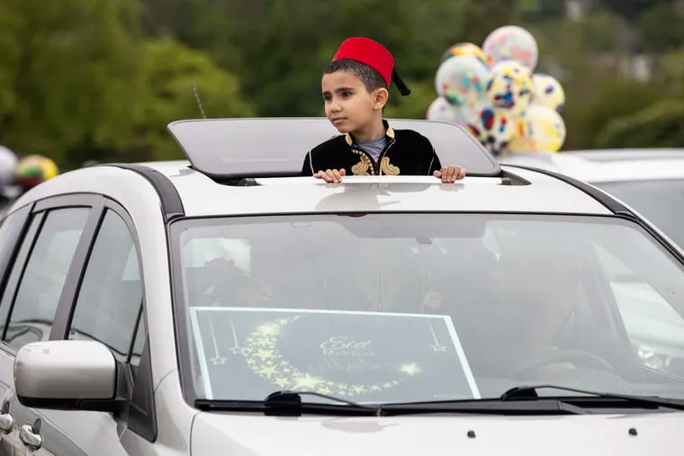 Rami Boufakhda, 9, of Delaware County, peeks out of the sunroof during the Muslim Society of Delaware Valley Eid car parade celebration in the parking lots of Willow Grove Park Mall in Willow Grove, Pa. on Sunday, May 24. Eid celebrates the end of the month of Ramadan.