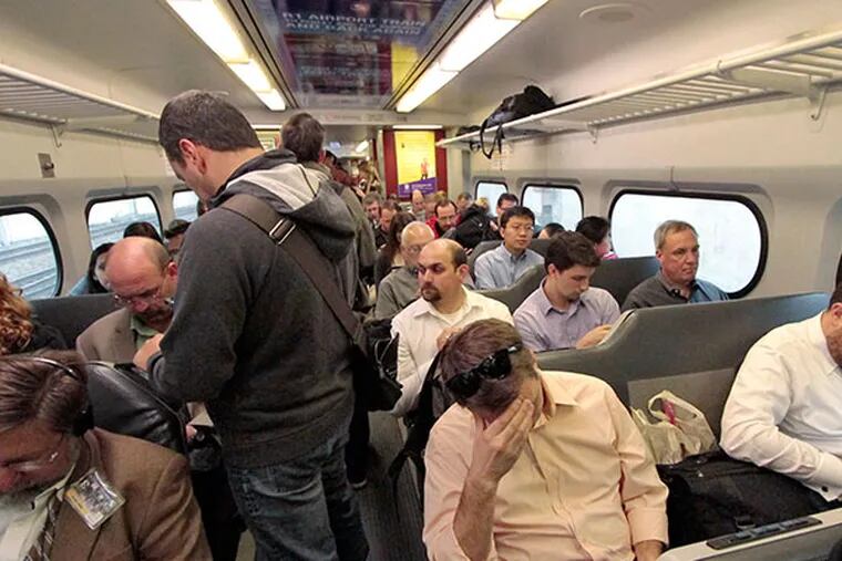 SEPTA passengers are forced to stand on the train while seated passengers place bags on empty seats. (Elizabeth Robertson/Staff Photographer)