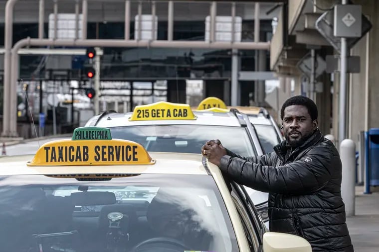 Taxi driver Frederick Andoh waits for customer near his taxi cab at the Philadelphia International Airport. Taxi drivers may soon have to pick up passengers at the airport in a different area.