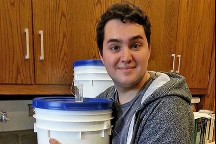 Senior Joseph Spearot, who brewed his own beer for a senior project, holds his fermentation vessel.