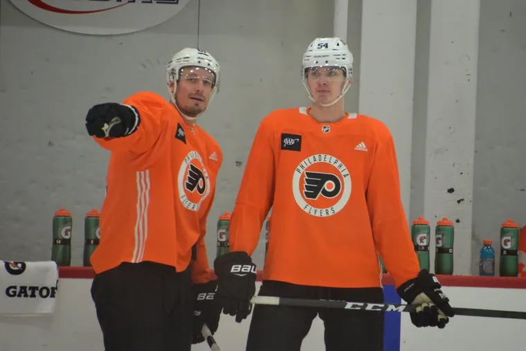 Flyers veteran defenseman Justin Braun gives some pointers to rookie Egor Zamula at a recent practice in Voorhees. Zamula, 21, made his NHL debut Tuesday in New Jersey.