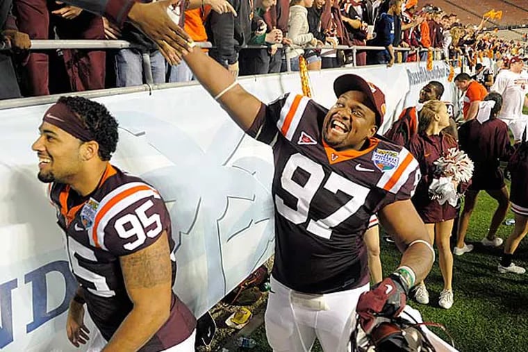 Virginia Tech defensives tackle Zack McCray (left) and Kris Harley (right) celebrate with fans following their 13-10 win in overtime of an NCAA college football Russell Athletic Bowl game against Rutgers, Friday, Dec. 28, 2012, in Orlando, Fla. (Brian Blanco/AP)