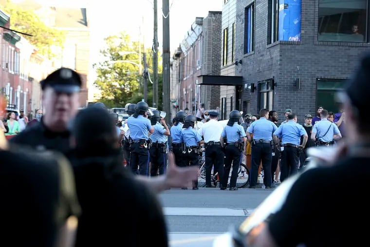 A police officer tries to talk to a group, foreground, who called themselves old-time Fishtowners, walking west on Girard Avenue carrying bats, hammers, and shovels in Philadelphia on Monday, June 1, 2020. The men said they believed they were protecting their neighborhood in the event looters or rioters showed up in the Fishtown neighborhood.