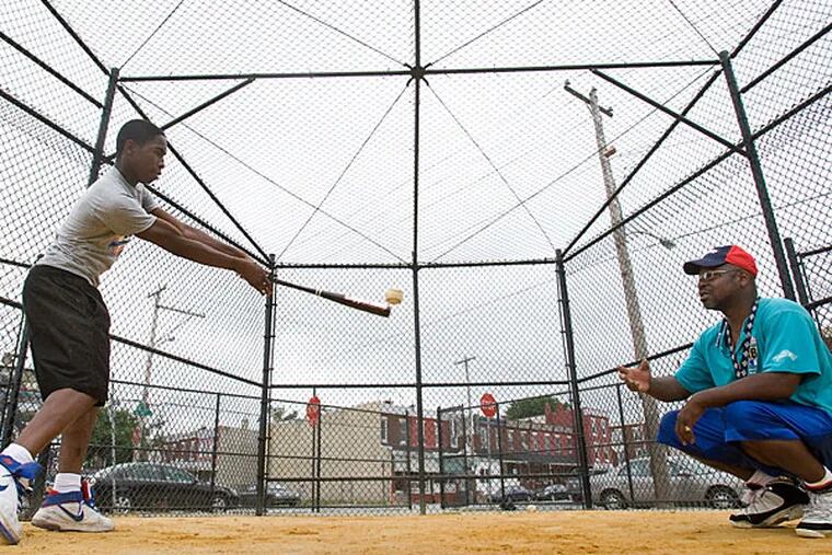 Michael Shenoster, 16, of Philadelphia, takes a swing at baseball tossed bycoach Kelly DuPree at Shepard Recreation Center. (David M Warren/Staff Photographer)