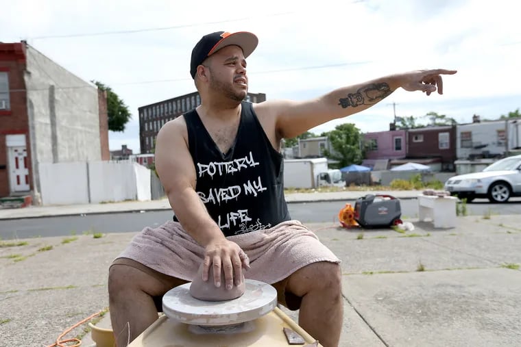 Award-winning ceramic artist Roberto Lugo points to an area where he use to graffiti as he does a pottery demonstration at E. Tusculum and Somerset streets in Philadelphia, PA on June 19, 2018.
