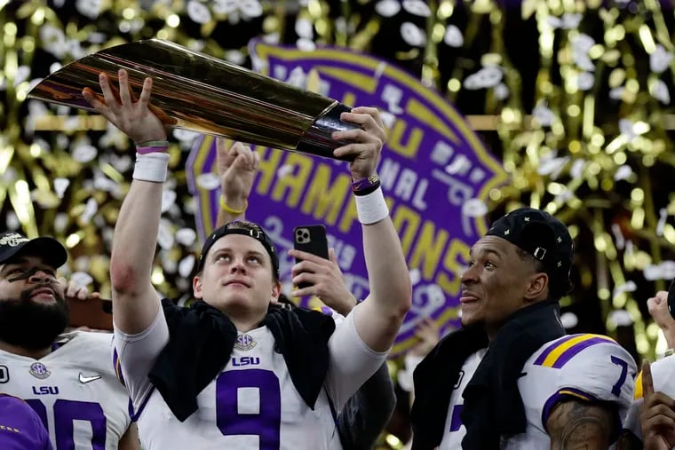 LSU quarterback Joe Burrow holds the trophy as safety Grant Delpit looks on after the Tigers defeated Clemson to win the title.