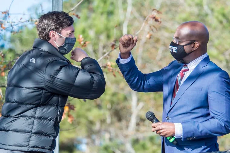 Jon Ossoff, left, and Raphael Warnock exchange elbow bumps during a campaign rally in Augusta, Ga. on Monday.