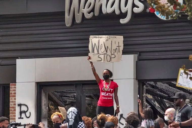 People hold a rally at Wendy's on University Avenue in Atlanta on Sunday. Rayshard Brooks died after a confrontation with police officers at the fast food restaurant in Atlanta on Friday.