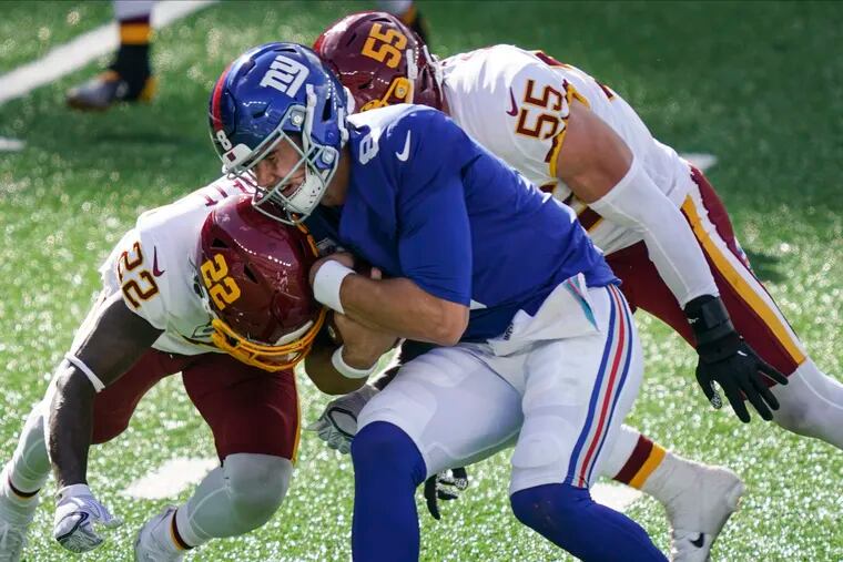 Giants quarterback Daniel Jones is tackled by Washington's Deshazor Everett (22) and Cole Holcomb (55) in last Sunday's game.