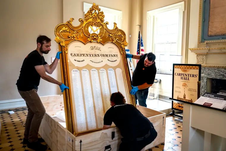 Workers from Atelier Fine Art Services, Matt Giordano (from left), Dan O’Donnell, and Kyle Choy, unbox one of two gilded frame membership boards they returned to Carpenters' Hall on Monday, June 26, 2023. The historic monument reopens to the public on July 3.