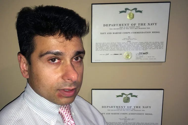 In his Doylestown law office, congressional candidate Dean Malik talks politics as his Marine Corps
commendations look on.