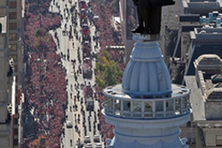 YONG KIM / Staff photographerIts curse apparently lifted, the statue of William Penn (left) gazes down on the Phillies&#0039; World Series parade from atop City Hall. Down on the street, fans (above) celebrate as the float carrying the 2008 World Series trophy and Shane Victorino passes by.