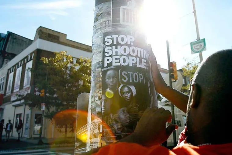 Terry Starks of Philadelphia Ceasefire tapes a poster to a pole near the scene of the subway shooting Wednesday, September 19, 2012. At least one teen was arrested. (Tom Gralish / Staff Photographer)