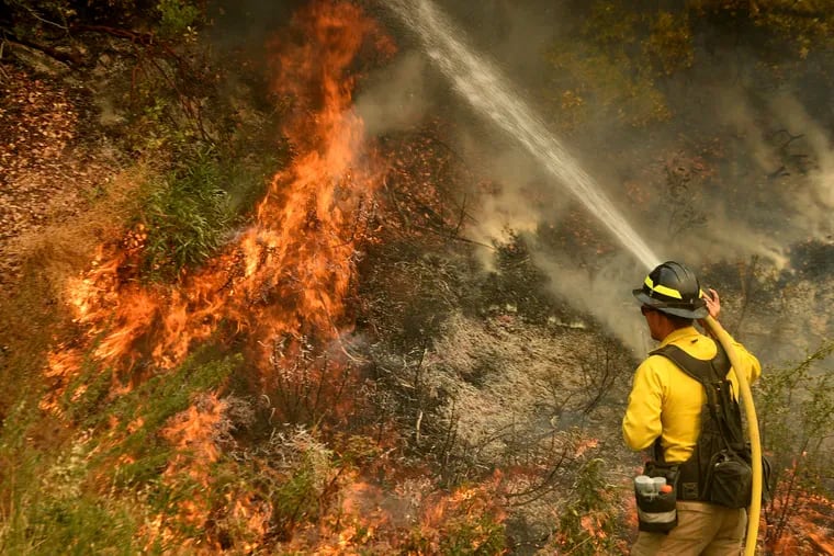 A firefighter puts out a hot spot along Highway 38 northwest of Forrest Falls, Calif., on Thursday.