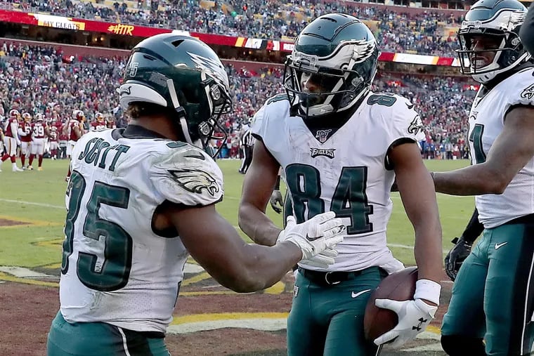Eagles running back Boston Scott, left, celebrates with wide receiver Greg Ward, center, after he scored a touchdown in the fourth quarter.