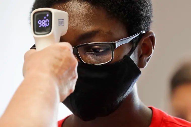 A student wearing a mask has his temperature checked by a teacher before entering a school in Texas in July. (AP Photo/LM Otero)