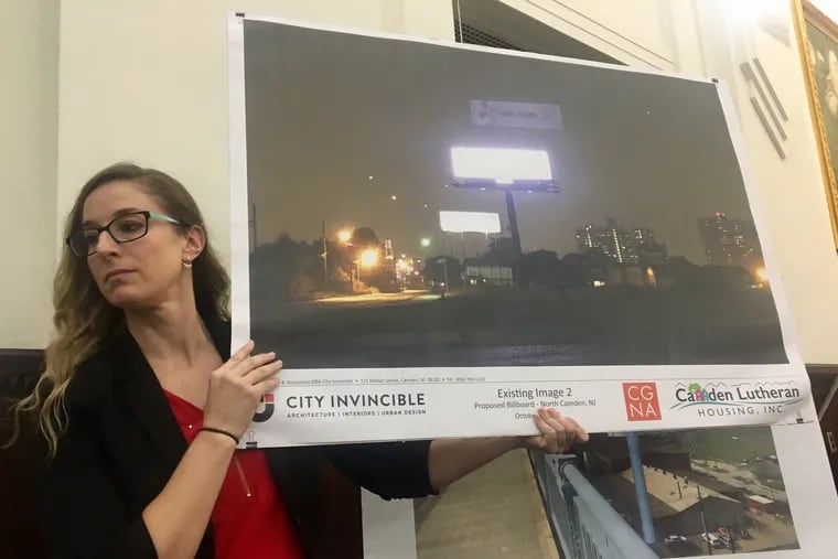 Jessica Franzini, director of Community Initiatives for Camden Lutheran Housing, holds up an example of a digital billboard. A 167-foot high digital billboard is proposed at the foot of the Ben Franklin Bridge.