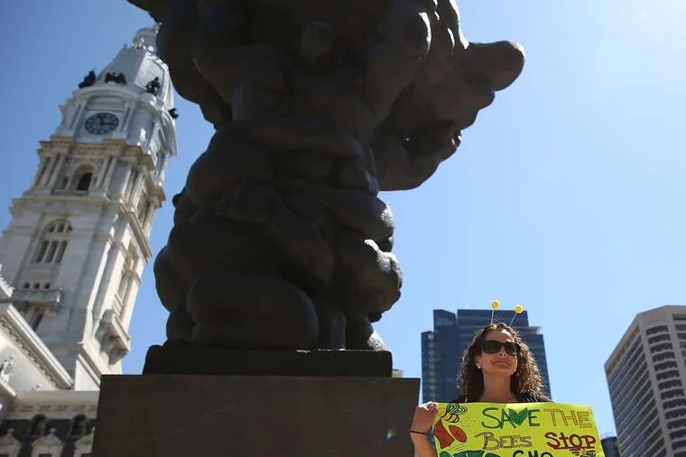 Dressed as a bee, protester Ashley Walsh of Ventnor, N.J., stands next to Jacques Lipchitz's sculpture "Government of the People" at MSB Plaza.