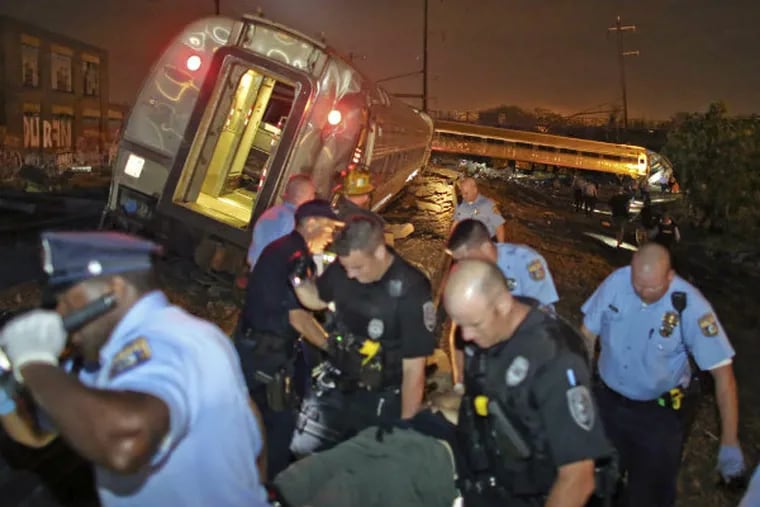 Emergency personnel help a passenger at the scene of a train wreck Tuesday, May 12, 2015, in Philadelphia. An Amtrak train headed to New York City derailed and crashed in Philadelphia. (AP Photo/Joseph Kaczmarek)