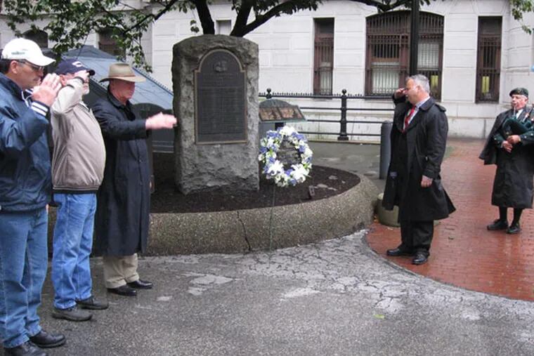 At a ceremony honoring fallen city police officers, Philadelphia fire fighters salute after union president Bill Gault (second from right) placed a wreath near a memorial in City Hall courtyard. Dell Campbell played bagpipes during the morning remembrance on Sept. 11, 2009,