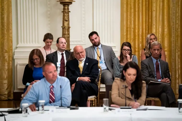 Centers for Disease Control Director Robert Redfield, with yellow tie at center, listening to the president in a July 7 roundtable discussion in Washington about reopening schools.