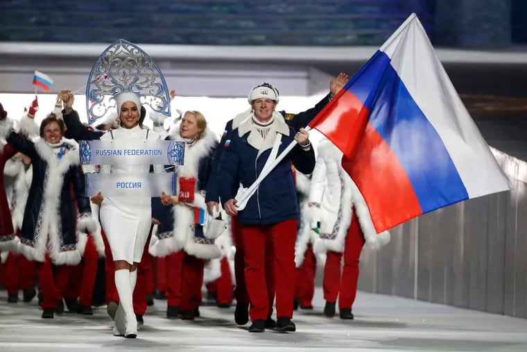 Alexander Zubkov of Russia carries the national flag as he leads the team during the opening ceremony of the 2014 Winter Olympics in Sochi, Russia. At left is model Irina Shayk carrying the Russian placard.