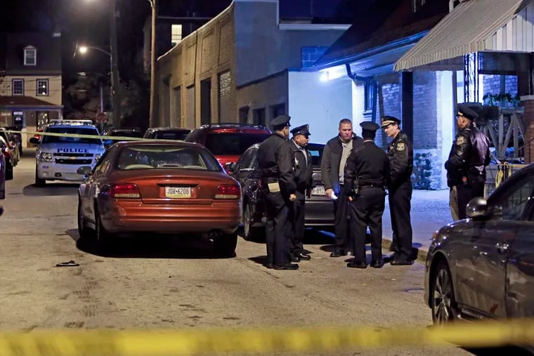 Investigators gather after police found Wayne Robert Ellington Sr. suffering from a gunshot wound inside a car on Marion Street near Queen Lane in the Germantown section of Philadelphia on Sunday Nov. 9, 2014. (For the Daily News/ Joseph Kaczmarek)