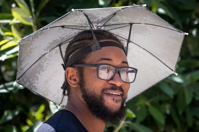 Khalil Crowell with the Office of Innovation and Technology wears his umbrella hat during the July heat at an event outside City Hall. Nature turned up the furnace around here in July and August.