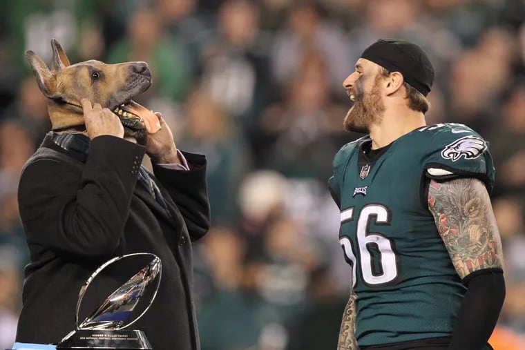 Eagle defensive end Chris Long, right, erupts in laughter as Terry Bradshaw dons a dog mask on the podium during the award ceremony for the NFC Championship on Sunday night.