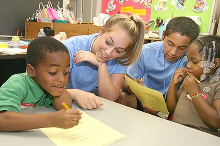 Lindsey Sample, left, is assisted on paper by Lauren Dorfman, second from left, of Council Rock South High School, as Jonathan Carmona, center, of the Pinelands, helps Nee'Na Lambert as part of a two-week program, the Urban Teacher Academy, at the Lanning Square School in Camden. (Charles Fox / Staff Photographer)