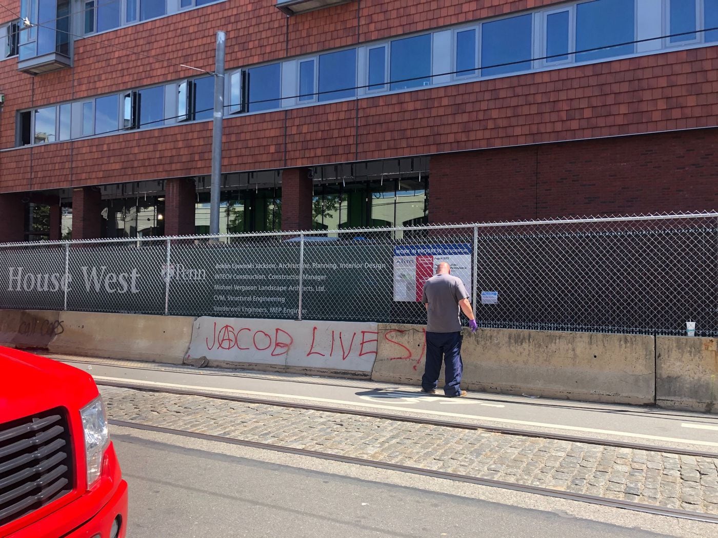 A worker power washes graffiti off of a construction barrier outside of a University of Pennsylvania residence hall Wednesday morning after a night of unrest saw demonstrators vandalizing buildings and breaking windows along 40th Street in West Philadelphia.