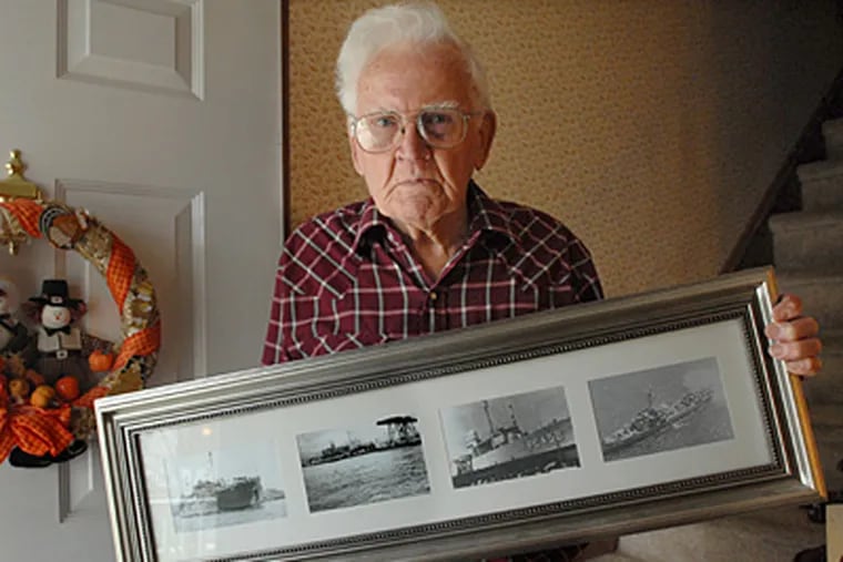 At his Burlington City, N.J. home, Pearl Harbor survivor Rowland Hoefle holds a framed group of photographs of ships on which he was stationed. ( April Saul / Staff Photographer )