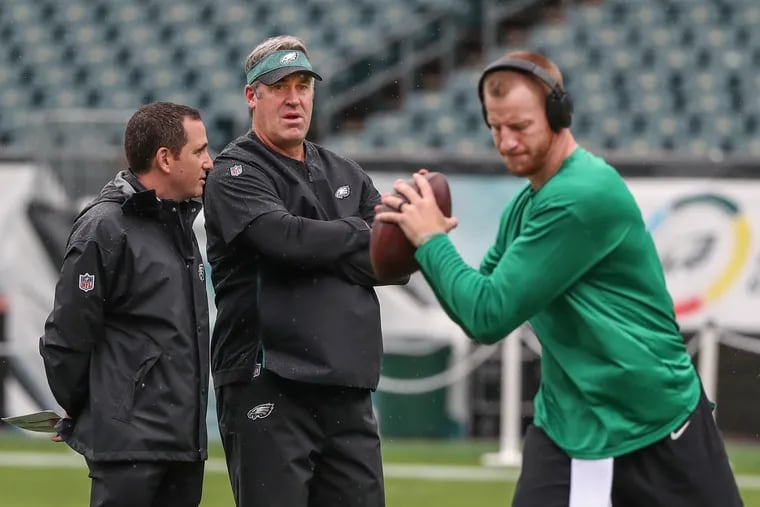 Eagles head coach Doug Pederson (center) has a choice to make this week. Will he start Carson Wentz (right), who was drafted by Howie Roseman (left), against the Saints?
